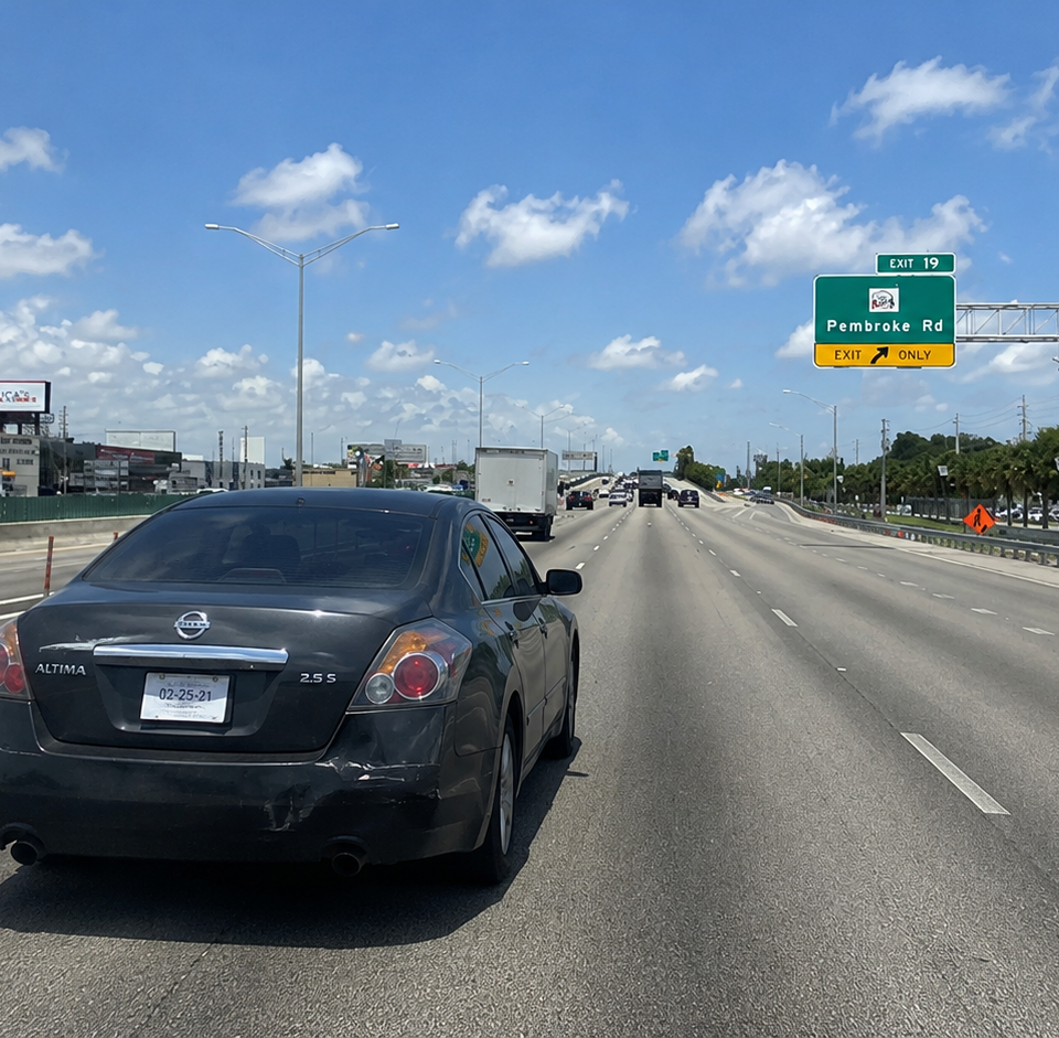 A chaotic traffic backup on I-95 in St. Johns County with brake lights, a damaged sedan, and a highway sign warning drivers to stop doing Altima stuff.