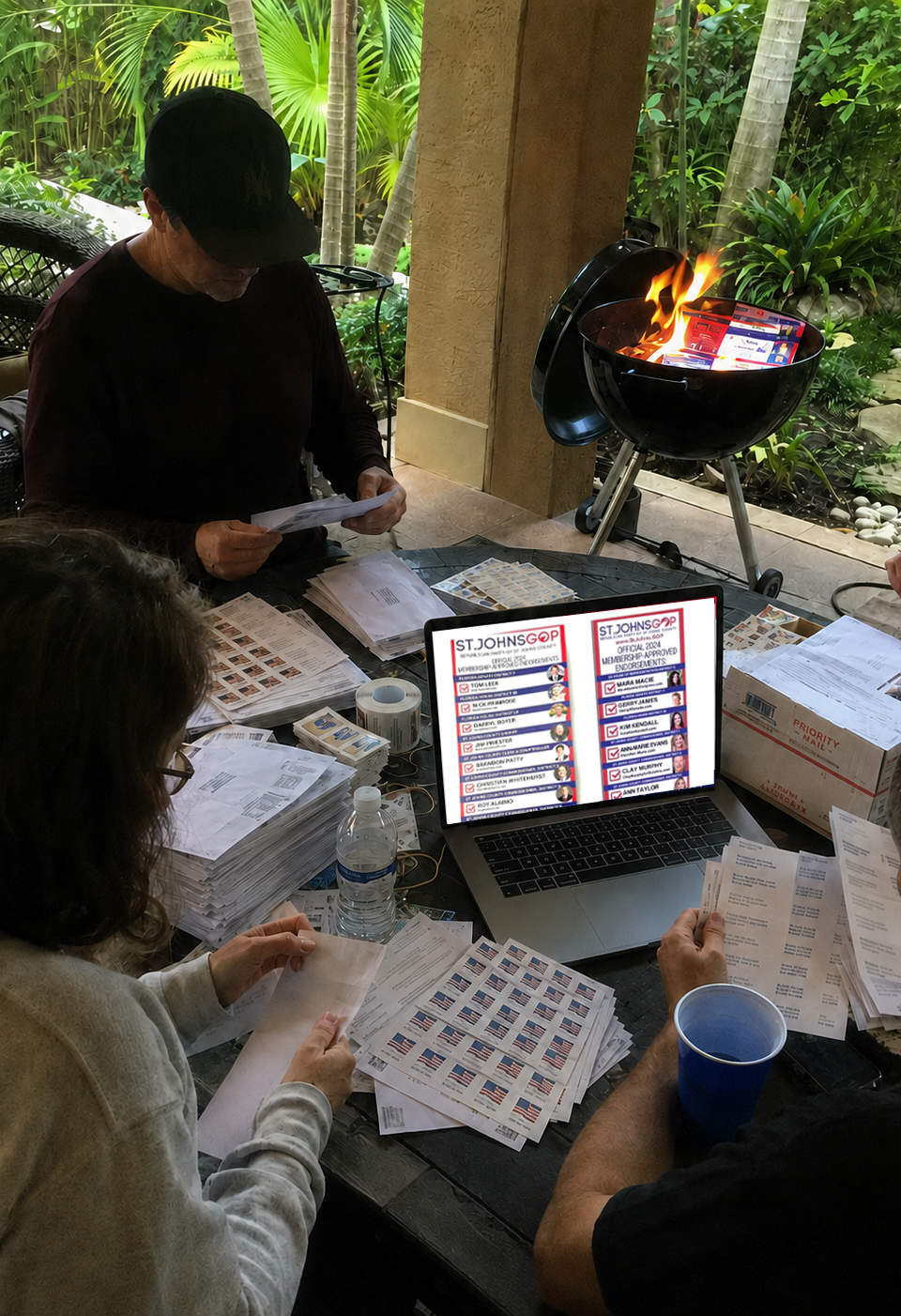 Satirical image of a laptop with Canva open beside envelopes, postage stamps, and a kettle grill in a florida backyard