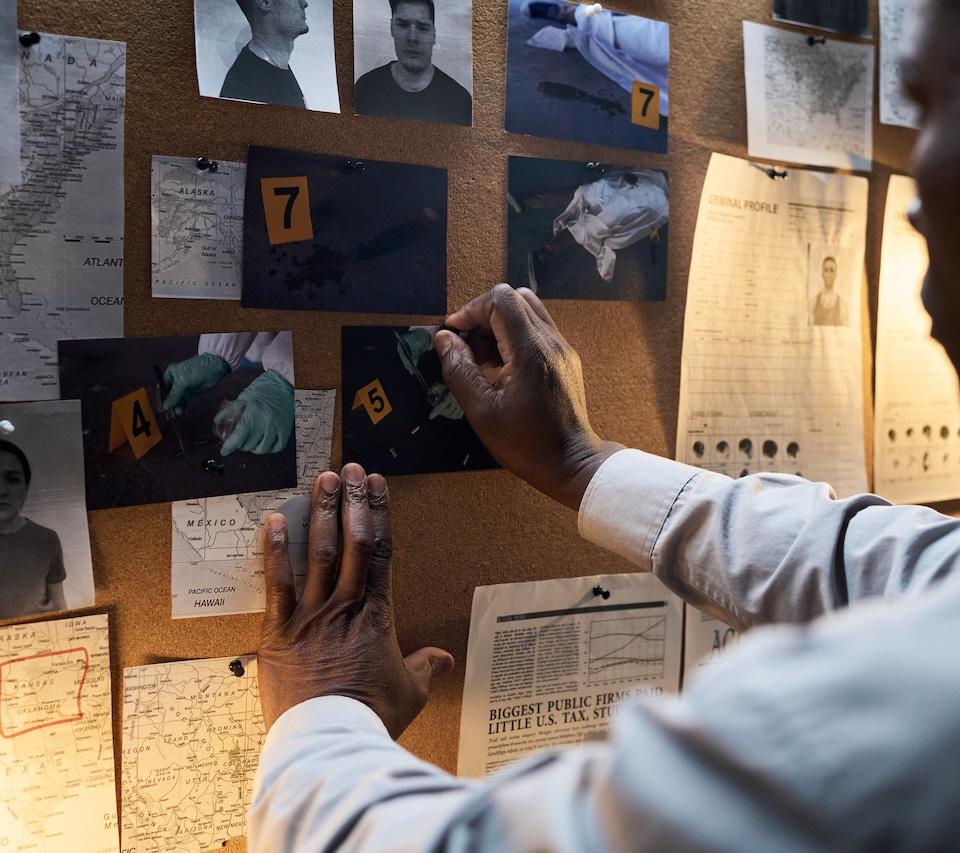 Investigator pinning a new crime scene photo to the wall.