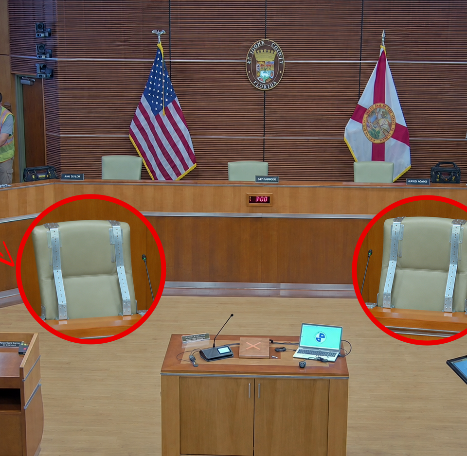 County facilities workers install hurricane straps on two empty commission seats inside the St. Johns County auditorium.